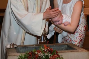 Arm von Priester und Mutter mit einem Baby, das getauft wird.