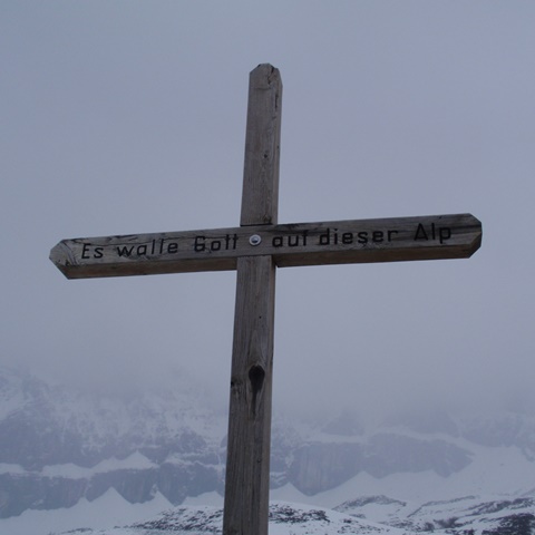 Kreuz auf Berggipfel vor Bergpanorama